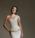 Woman wearing a white sleeveless top and skirt set against a plain background