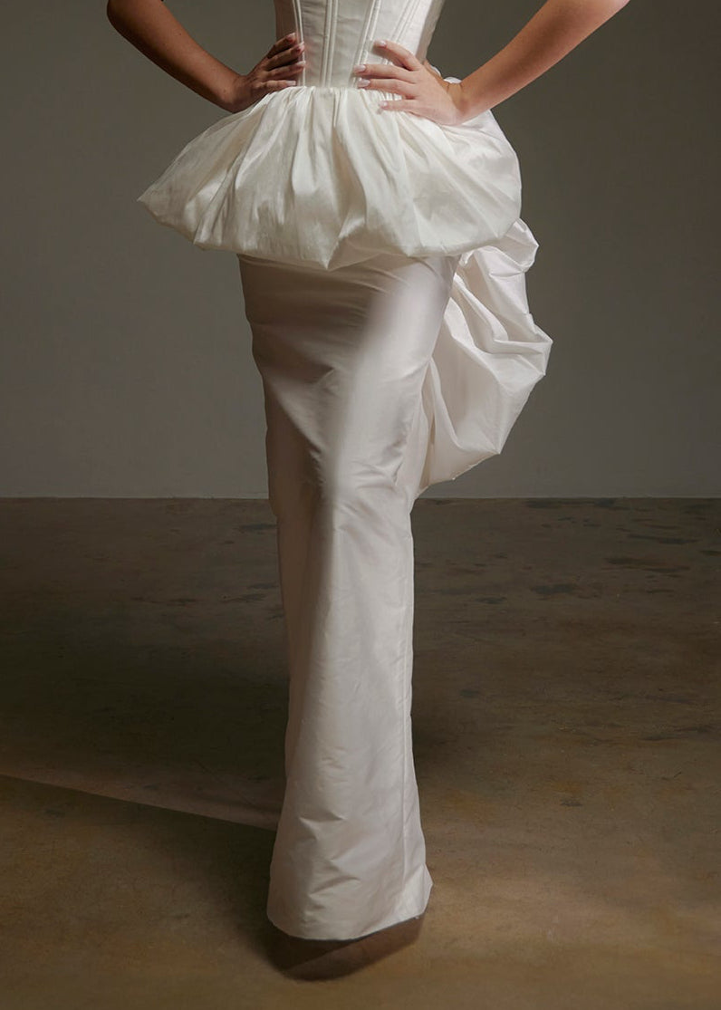 Woman wearing a white wedding dress with a veil against a dark background