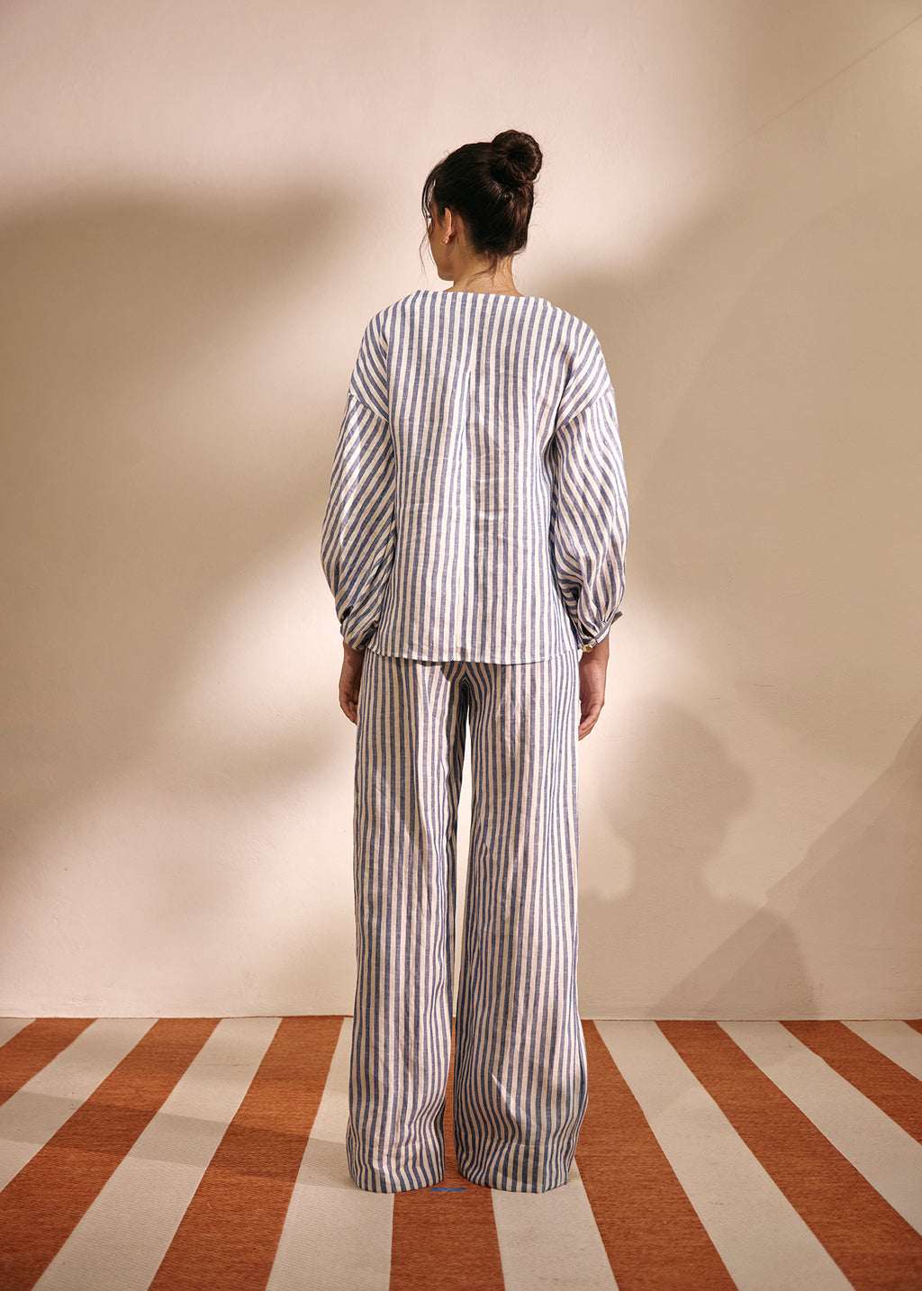 gil wearing a two piece blouse and pant in striped linen white and navy blue