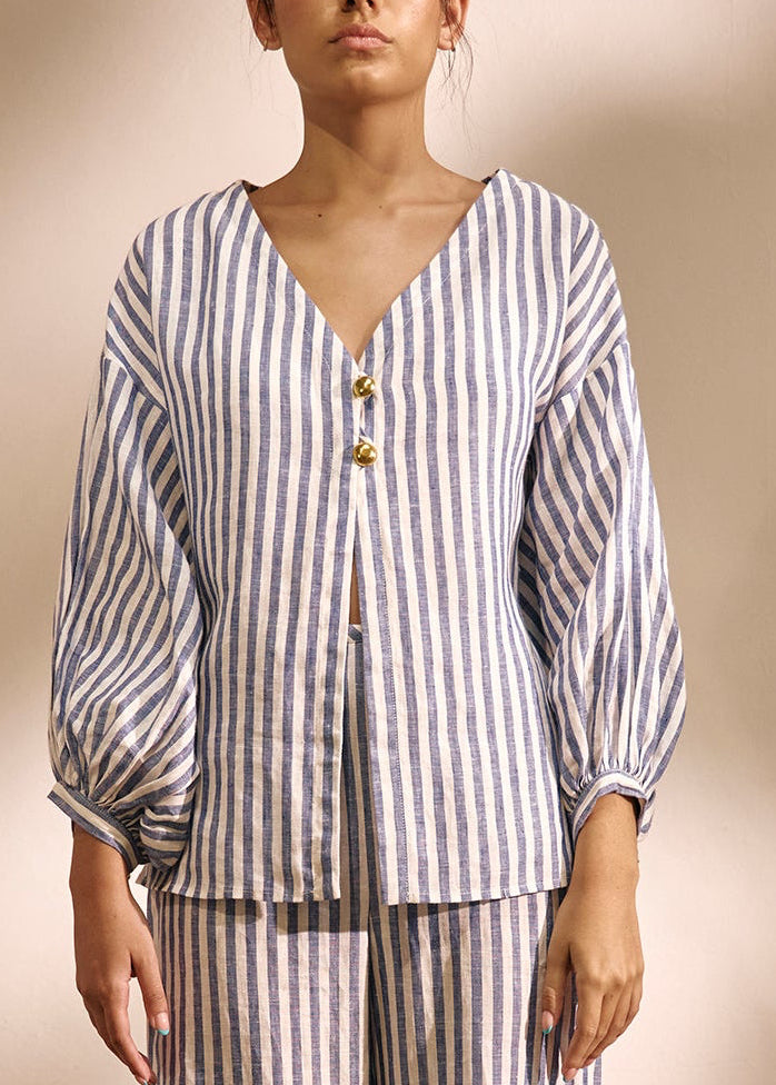woman wearing a two piece striped blue and white  blouse and linen set gold buttons 