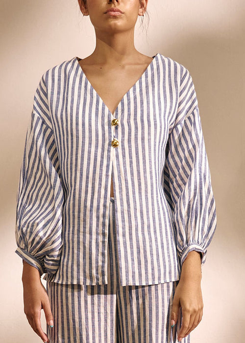 woman wearing a two piece striped blue and white  blouse and linen set gold buttons 